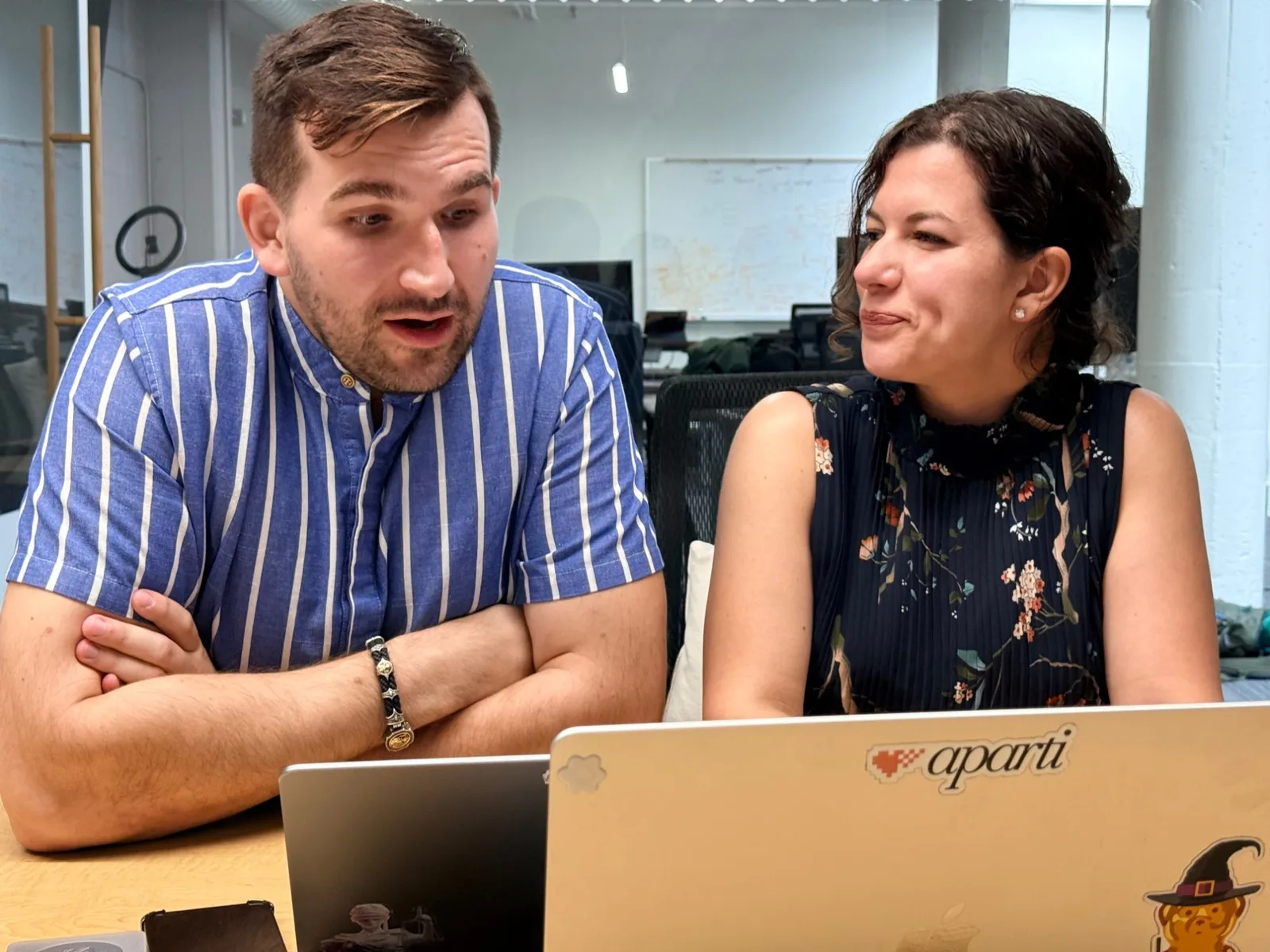 Igor Sheremet and Anna Naidis of Aparti sitting side by side at a laptop displaying the Aparti heart logo, in conversation in the Aparti office.