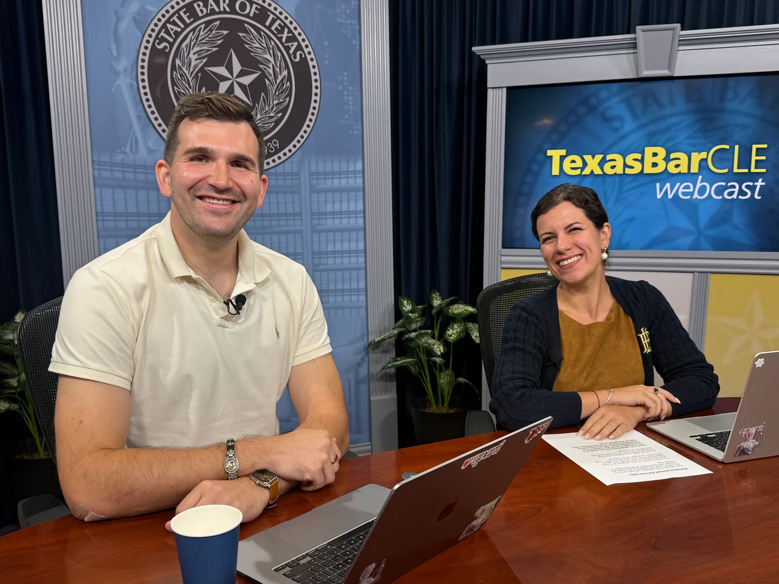 Two presenters with laptops and microphones at the TexasBarCLE desk beside a screen displaying TexasBarCLE webcast.
